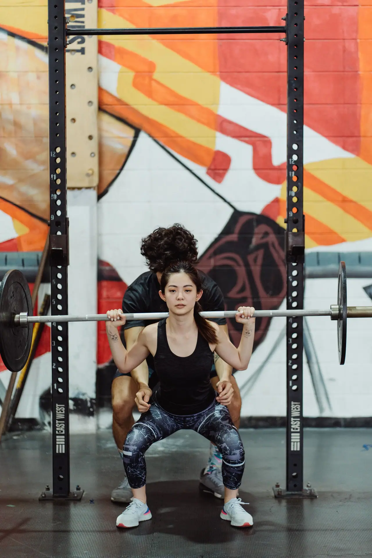 A coach spotting a lifter through a back squat in a power rack